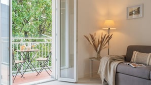 A room with a balcony, a sofa, a lamp, and a vase with dried plants. - Magnolia House Como by Rent All Como (Como)