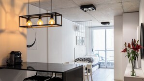 A modern kitchen with a black countertop, two bar stools, and a hanging light fixture. - BT Homes - Palermo, Oro  (Buenos Aires)