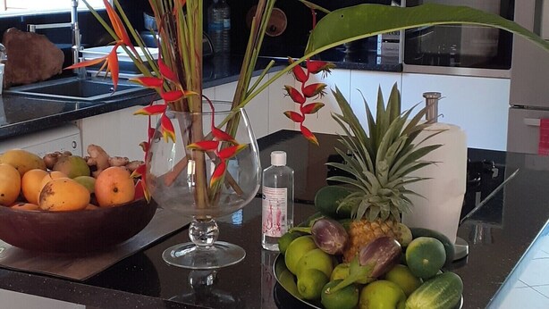 A kitchen counter with a fruit bowl, a vase with flowers, and a microwave.