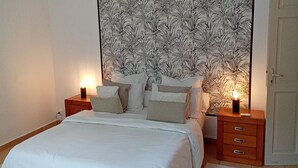 A bedroom with a large bed, two bedside tables with lamps, a ceiling fan, and a patterned headboard.