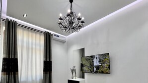 A modern bedroom with a bed, a mounted TV, a chandelier, and a wall-mounted air conditioning unit. - Bibigon 31 (Tashkent)