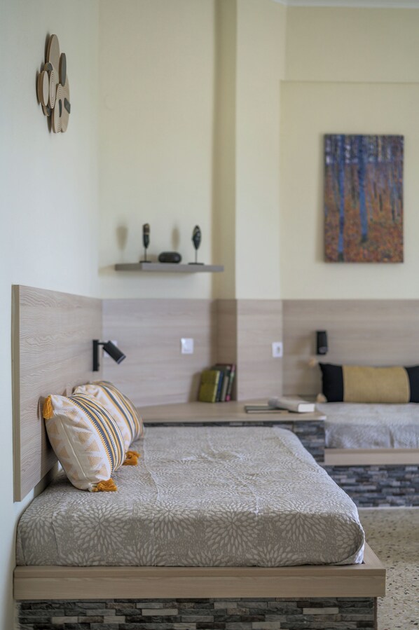 A neatly arranged bedroom with a bed, a bedside table, a lamp, and a painting on the wall.