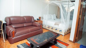 Une pièce avec un canapé en cuir marron, un lit à baldaquin et une petite table.