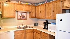 A kitchen with wooden cabinets, a white refrigerator, a microwave, and a sink. - Train View a spacious 3-bedroom upstairs apartment with WiFi in Northfork (Northfork)