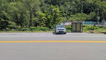 A road with a bus stop and a car parked on the side.