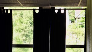 A room with a wicker chair, a small table with a lamp, and a window with curtains. - Train View a spacious 3-bedroom upstairs apartment with WiFi in Northfork (Northfork)