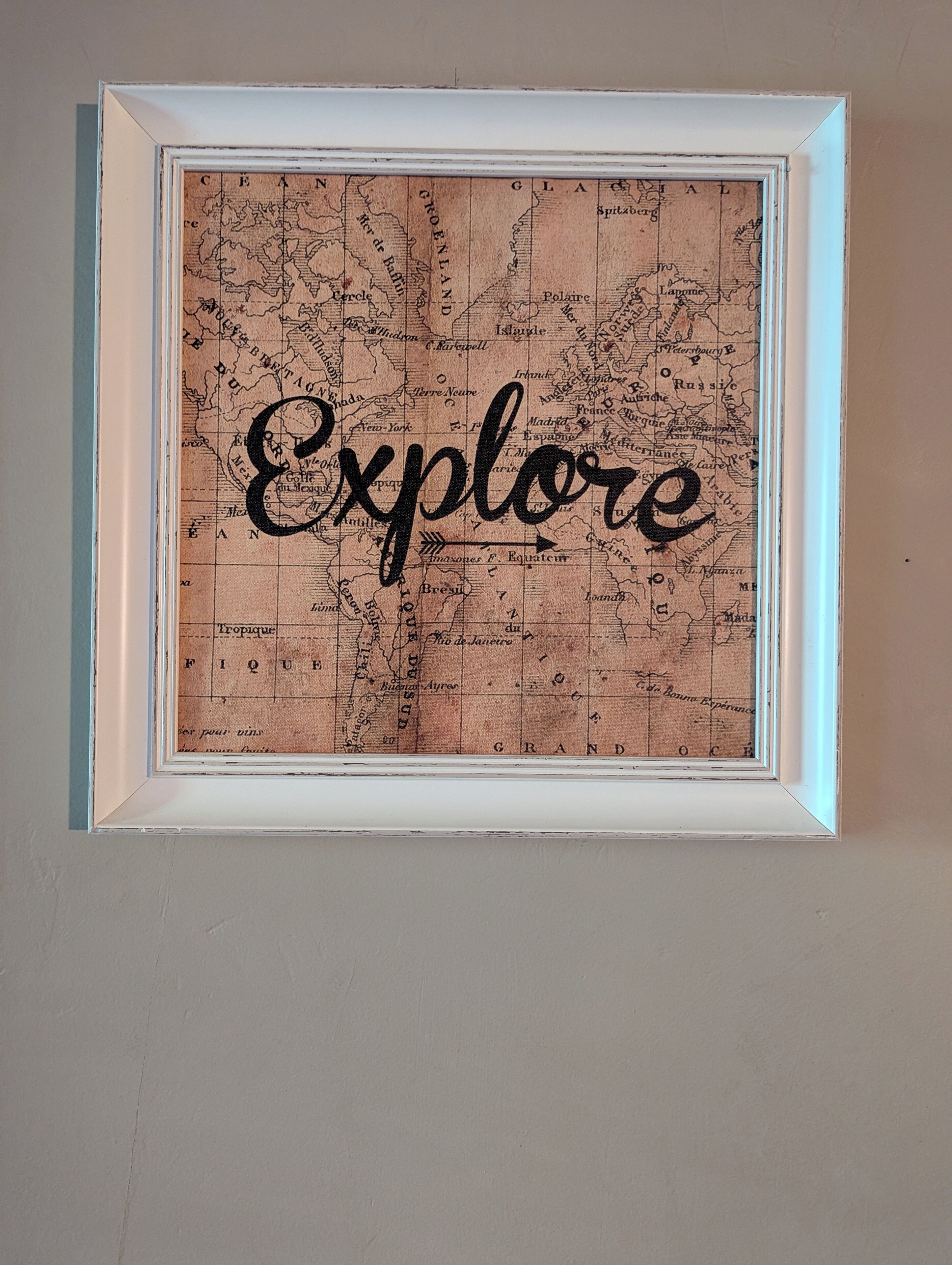A corkboard with the word "Explore" written on it, framed and hung on a wall.