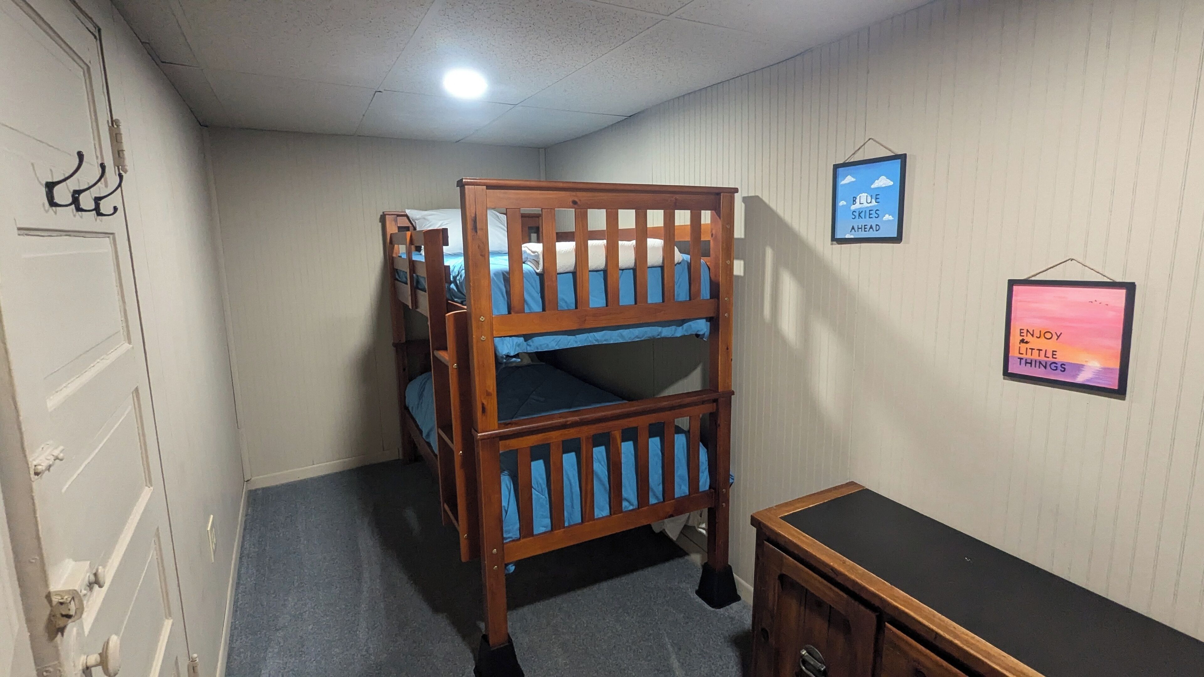 A room with bunk beds, a desk, and two wall decorations.