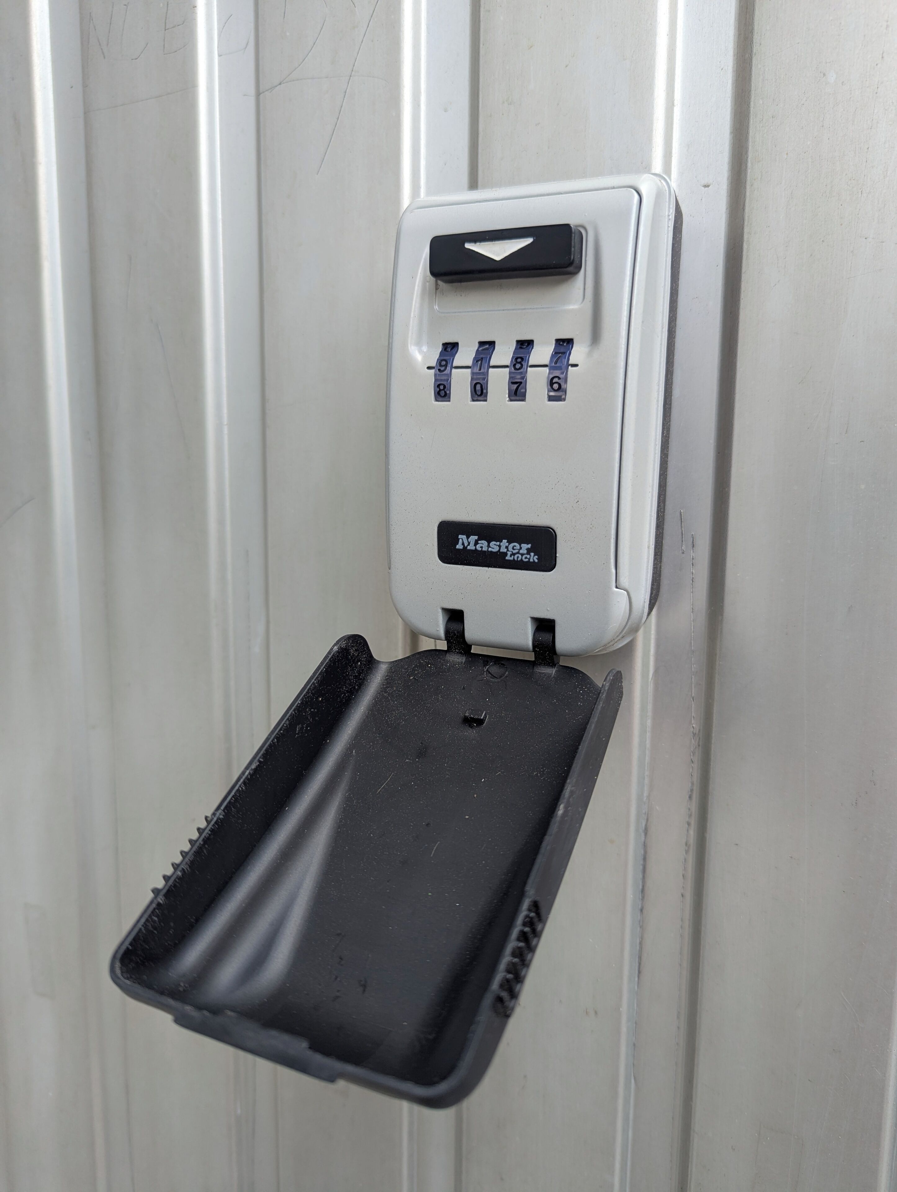 A Master Lock combination padlock on a white door.