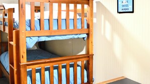 A bunk bed with a wooden frame and blue bedding, a small wooden dresser, and a framed picture on the wall. - Train View a spacious 3-bedroom upstairs apartment with WiFi in Northfork (Northfork)