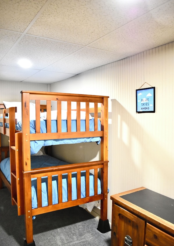 A bunk bed with a wooden frame and blue bedding, a small wooden dresser, and a framed picture on the wall. - Train View a spacious 3-bedroom upstairs apartment with WiFi in Northfork (Northfork)