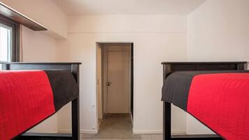 A room with two bunk beds, a door, and a window.