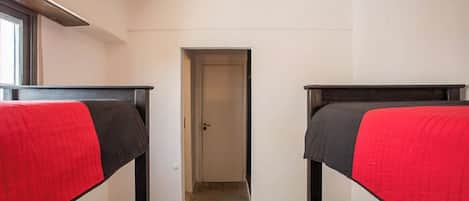 A room with two bunk beds, a door, and a window.