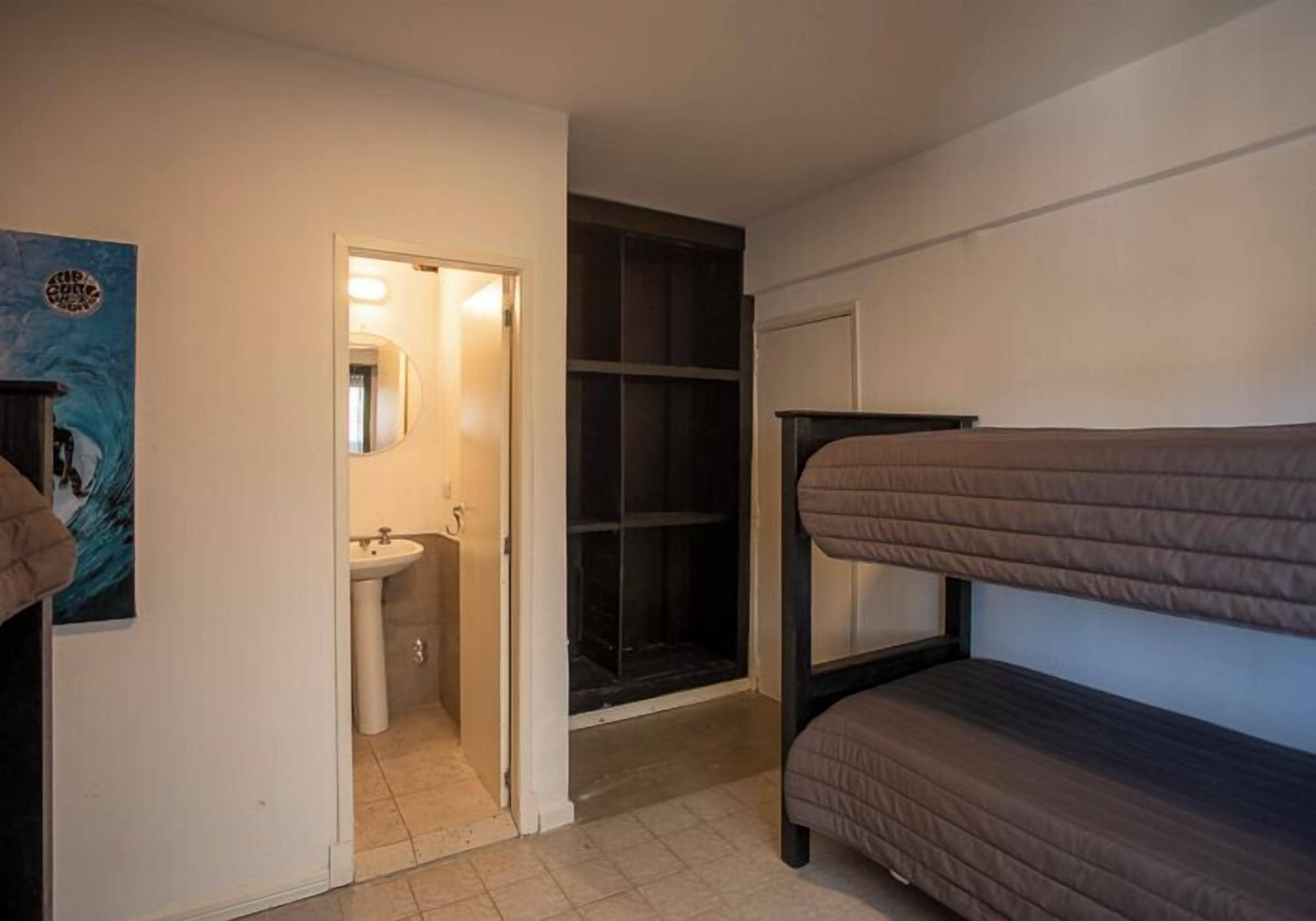 A room with bunk beds, a sink, a mirror, and a wardrobe.