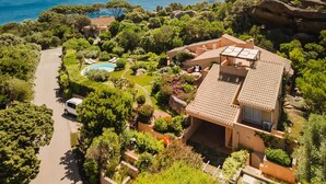 Una villa de estilo mediterráneo con piscina, jardines exuberantes y vistas al mar.