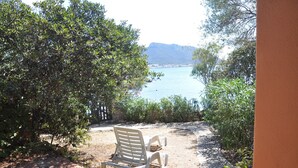 A patio with two white plastic chairs overlooking a body of water and mountains.