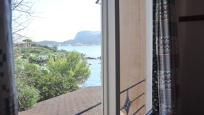 A view from a balcony overlooking a coastal area with greenery and a body of water.