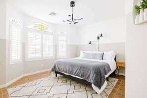 Ein Schlafzimmer mit einem Bett, einem Schreibtisch, einem Stuhl, einer Lampe und einem Fenster mit Blick.