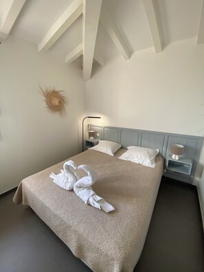 Een hotelkamer met een bed, nachtkastje, lamp en een decoratie aan de muur.
