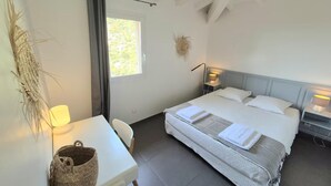 A bedroom with a bed, bedside tables, a desk, and a window.