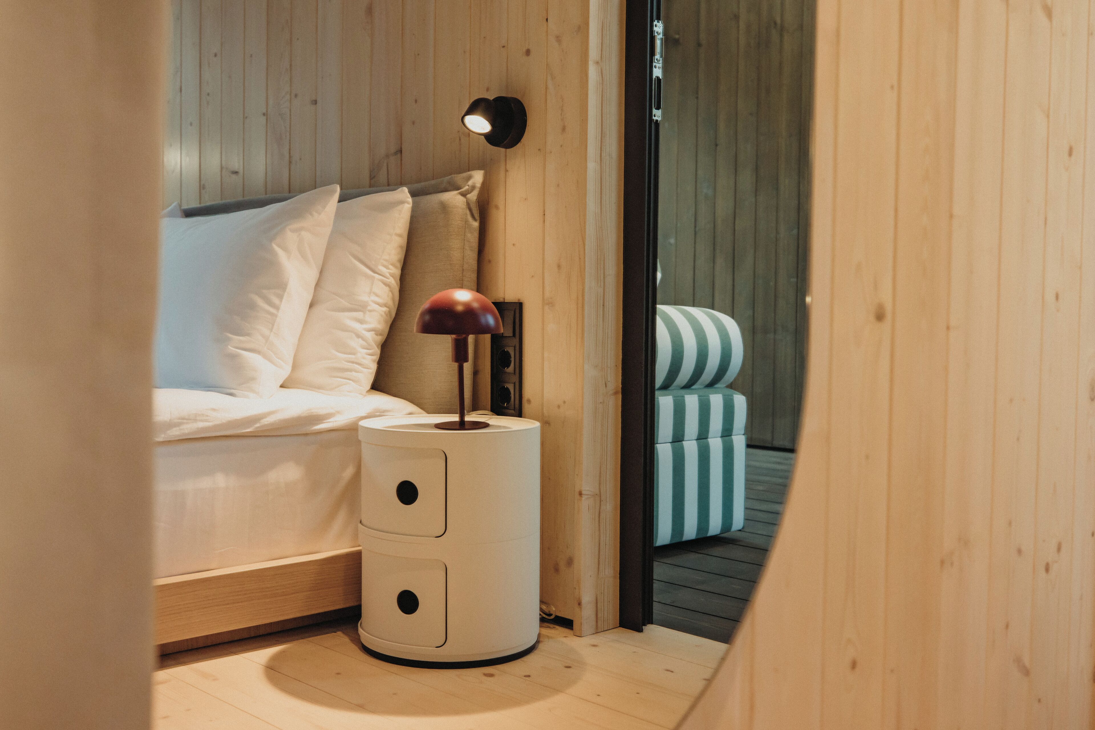 A bedroom with a bed, a bedside lamp, and a small table with drawers.