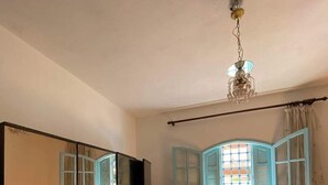 Ein Schlafzimmer mit Bett, Kleiderschrank, Spiegel und einem Fenster mit Fensterläden.