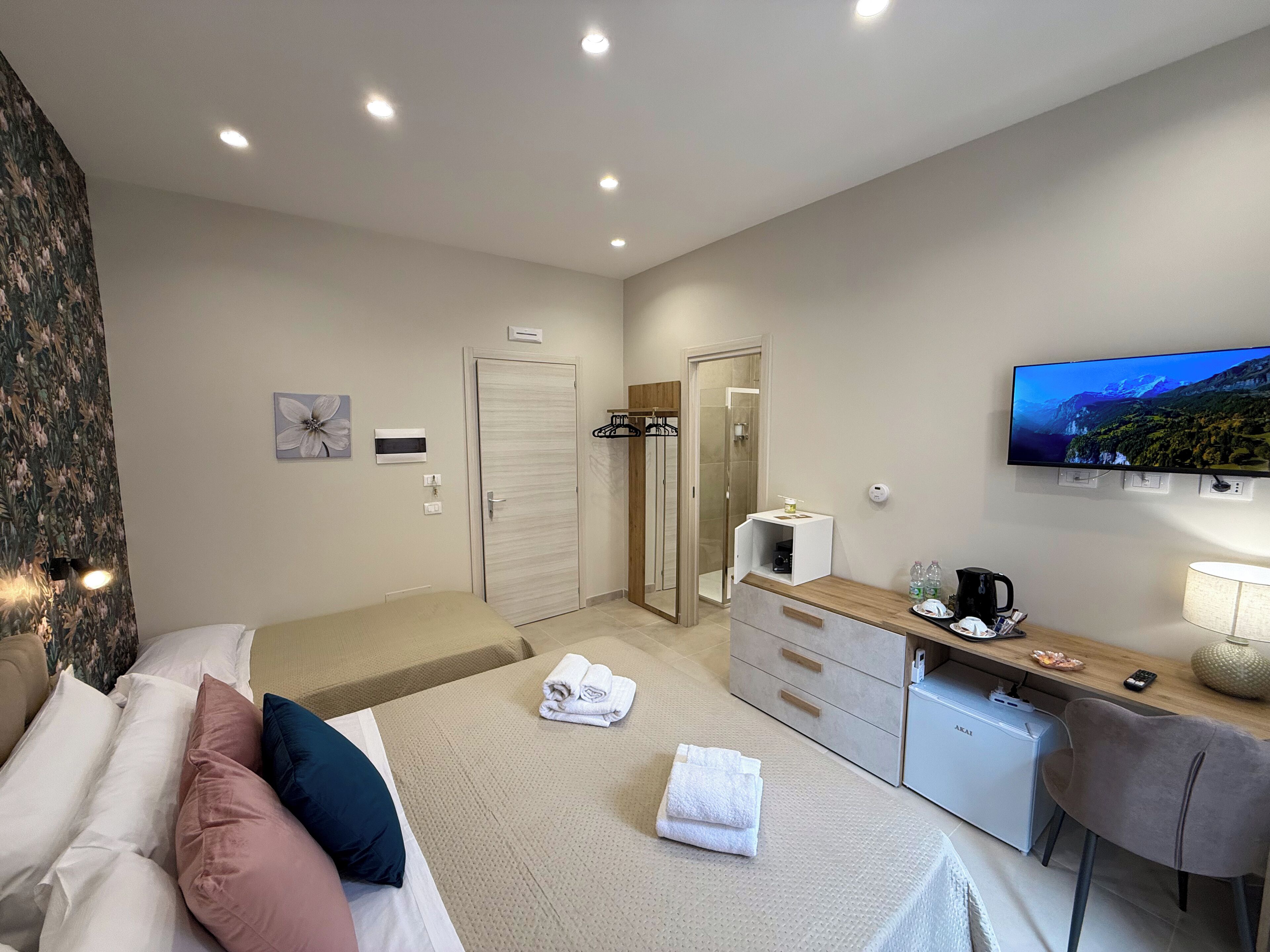Ein Hotelzimmer mit Bett, Schreibtisch, Fernseher und Duschbereich.
