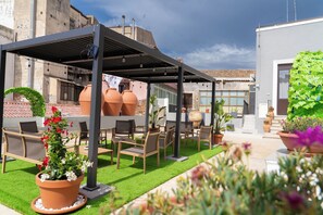 An outdoor patio with a pergola, seating area, and potted plants. - B&B Town house 54 (Catania)