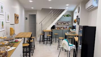 A modern kitchen with a central island, bar stools, a refrigerator, and a staircase leading to an upper level.
