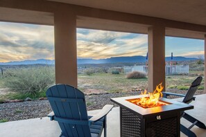 Eine Terrasse mit Adirondack-Stühlen, einer Feuerstelle und Blick auf die Berge.