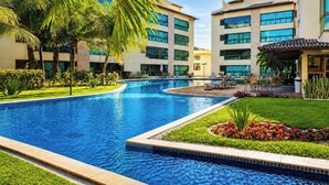 Una piscina rodeada de palmeras y un edificio con varias ventanas.