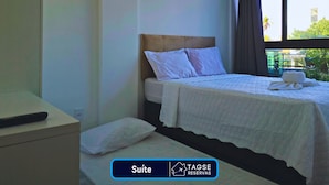 A hotel room with a bed, a bedside table, and a window with curtains.