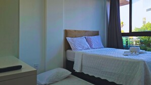 A hotel room with a bed, a bedside table, and a window with curtains. - CAP003 | Complete Apt Just 100m from the Beach (Ipojuca)