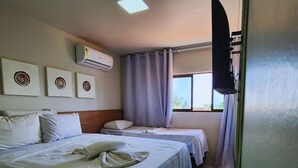 A hotel room with two beds, a ceiling fan, air conditioning, a window with curtains, and artwork on the wall. - POR012 | 3-Suite Apartment in Porto de Galinhas (Ipojuca)