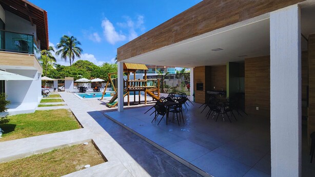 A modern outdoor patio with a pool, play area, and dining setup. - POR012 | 3-Suite Apartment in Porto de Galinhas (Ipojuca)