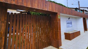 A modern building with a wooden fence and a sign indicating a temporary parking area. - GRA325 | Spacious Retreat with Pool and Barbecue. (Gravatá)