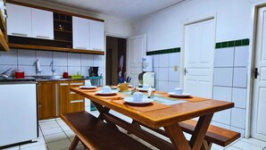 A compact kitchen with white cabinets, a wooden table set for four, and a bench. - GRA325 | Spacious Retreat with Pool and Barbecue. (Gravatá)