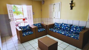 A room with a wicker sofa set, a small table, and a door leading outside. - GRA325 | Spacious Retreat with Pool and Barbecue. (Gravatá)