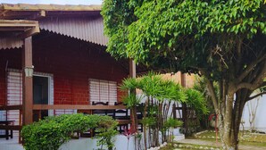 A traditional building with a tiled roof, a balcony with a railing, and a garden area with a pathway and various plants. - GRA325 | Spacious Retreat with Pool and Barbecue. (Gravatá)