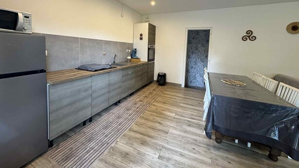 A modern kitchen with grey cabinets, a built-in microwave, and a wooden countertop.