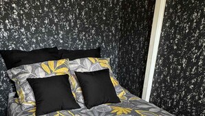 A bed with a floral-patterned bedspread and two black pillows.