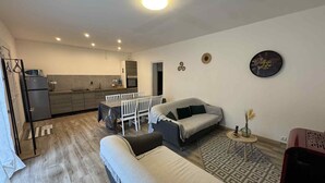 A compact living space with a kitchenette, a dining area, and a seating area with a sofa and a patterned rug.