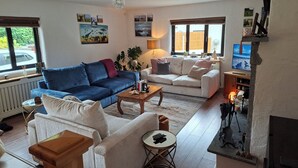 Un salon avec un canapé bleu, un canapé blanc, une table basse et une cheminée.
