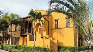 A yellow building with a balcony and palm trees. - 3Bedroom 2.5 bath townhome in beautiful Naples Florida

: (Naples)