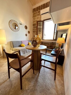 Un salon chaleureux avec un mur en pierre, une table ronde et un canapé.