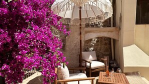A patio with a wooden chair and table, a white umbrella, and vibrant pink bougainvillea flowers. - ALGHERO CENTER LOFT MARIS IN SULIS SQUARE: ICONIC WATERFRONT LOFT-TOP LOCATION (Alghero)