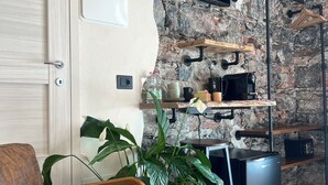 A modern kitchen with a stone wall, built-in shelves, a flat-screen TV, and a refrigerator. - La Campanula (La Spezia)
