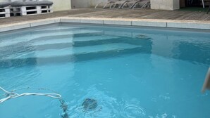 Una piscina con sillas de descanso y zona de barbacoa.