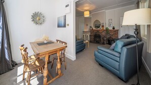 Een woonkamer met een eettafel, een blauwe bank en een open haard.