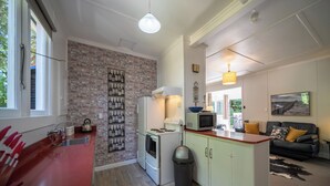 Een compacte keuken met een bakstenen muur, een koelkast, een magnetron en een spoelbak.